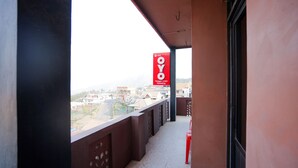 A balcony with a red sign, a view of buildings, and a red chair. - OYO 1378 Tengger Indah Homestay (Ngadisari)