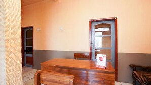 A wooden dining table with chairs, a wooden bench, and a door with a window. - OYO 1378 Tengger Indah Homestay (Ngadisari)