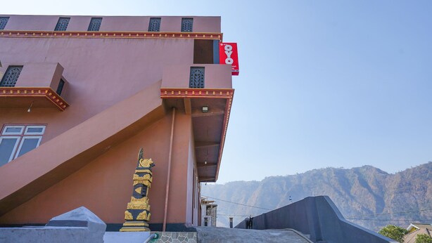 A building with a pink facade, a golden statue, and a red sign. - OYO 1378 Tengger Indah Homestay (Ngadisari)