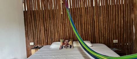 Une pièce avec un lit, un mur recouvert de lattes de bois et un hamac.
