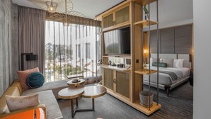 Et moderne hotelværelse med en sofa, to runde borde, et fjernsyn og en seng.