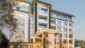Et moderne hotel med glasfacade, flere balkoner og et anlagt indgangsområde.