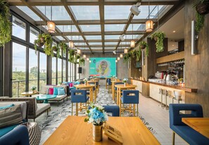 A modern cafe with a high ceiling, hanging plants, and a bar area. - The Social House Nairobi, a Preferred Lifestyle Hotel (Nairobi)