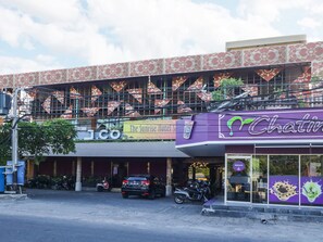 Een hotel met een paarse gevel en een bordje met de tekst 'The Sunrise Hotel'.