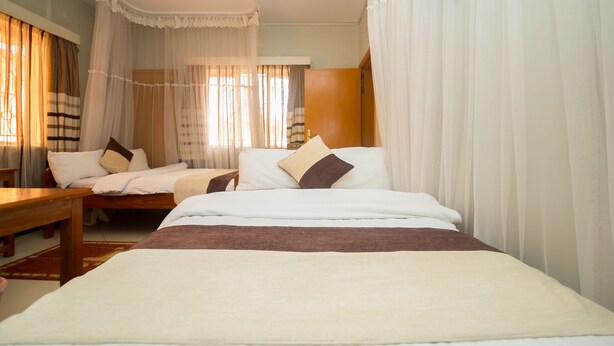 Una habitación de hotel con una cama grande, dos mesitas de noche y un banco.
