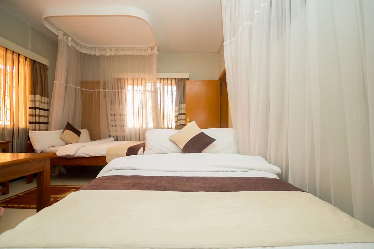A hotel room with a large bed, two bedside tables, and a bench.