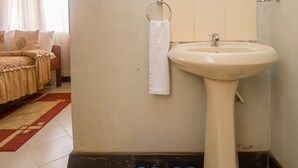 Un baño con lavamanos, espejo y un par de zapatillas azules en el suelo.