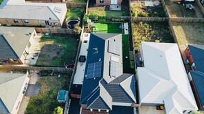 Houses with diverse roof styles and solar panels surround a well-manicured lawn featuring a playground.