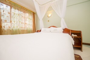 A neatly made bed with white linens and two pillows labeled "Jupiter Lang'ata". - Jupiter Guest Resort Langata (Nairobi)