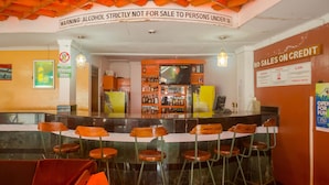 Zona de bar con taburetes, mostrador y pantalla de televisión.