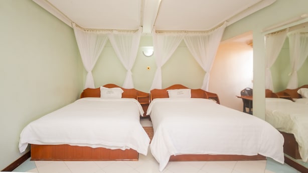 Una cama doble con ropa de cama blanca, cabecera de madera y dosel.