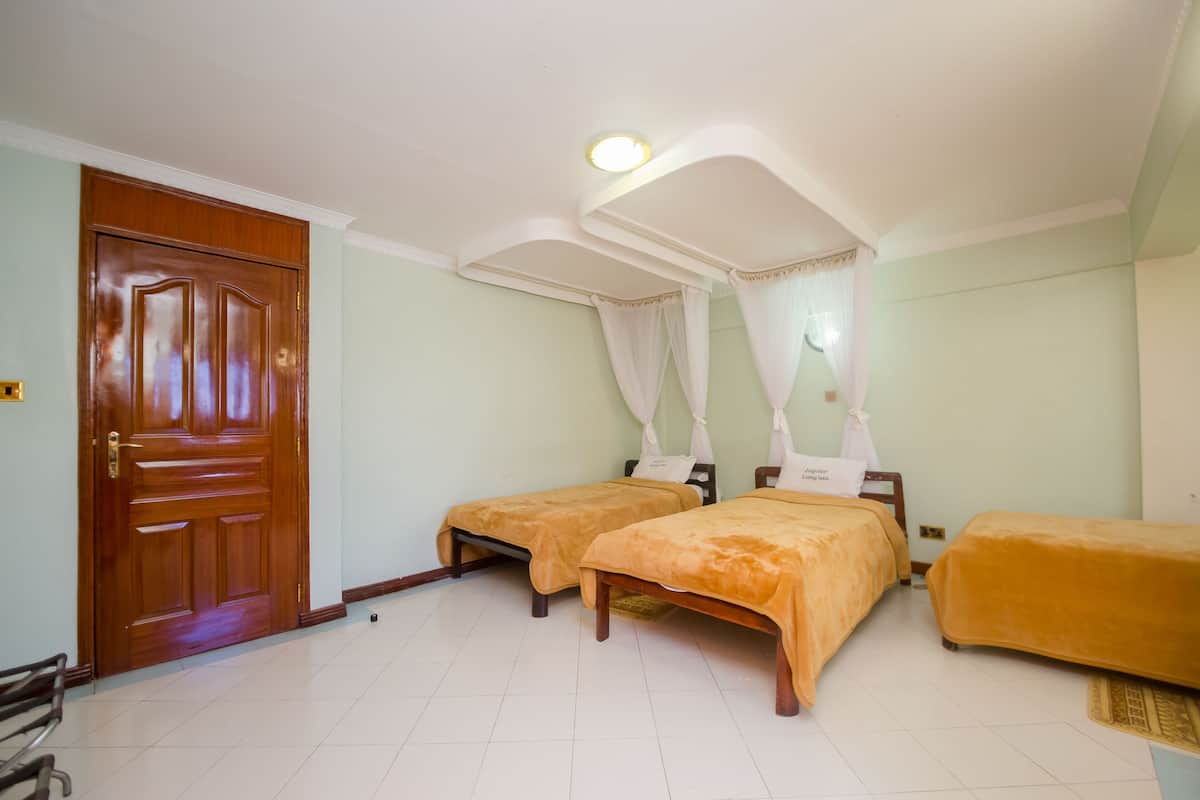 A room with two beds, a wooden door, and a ceiling light.