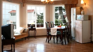 A dining area with a wooden table, chairs, and a white refrigerator. - Dasom Pension (Seogwipo)