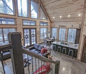 A spacious cabin with a large dining area, a cozy seating area with a sofa and cushions, and a kitchen with bar stools.