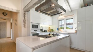 Une cuisine moderne avec des meubles blancs, un îlot central, un four à micro-ondes et une fenêtre donnant sur un balcon.