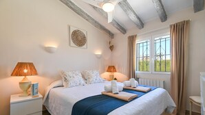 Une chambre à coucher avec un lit, des lampes de chevet, une fenêtre avec des rideaux et un radiateur.