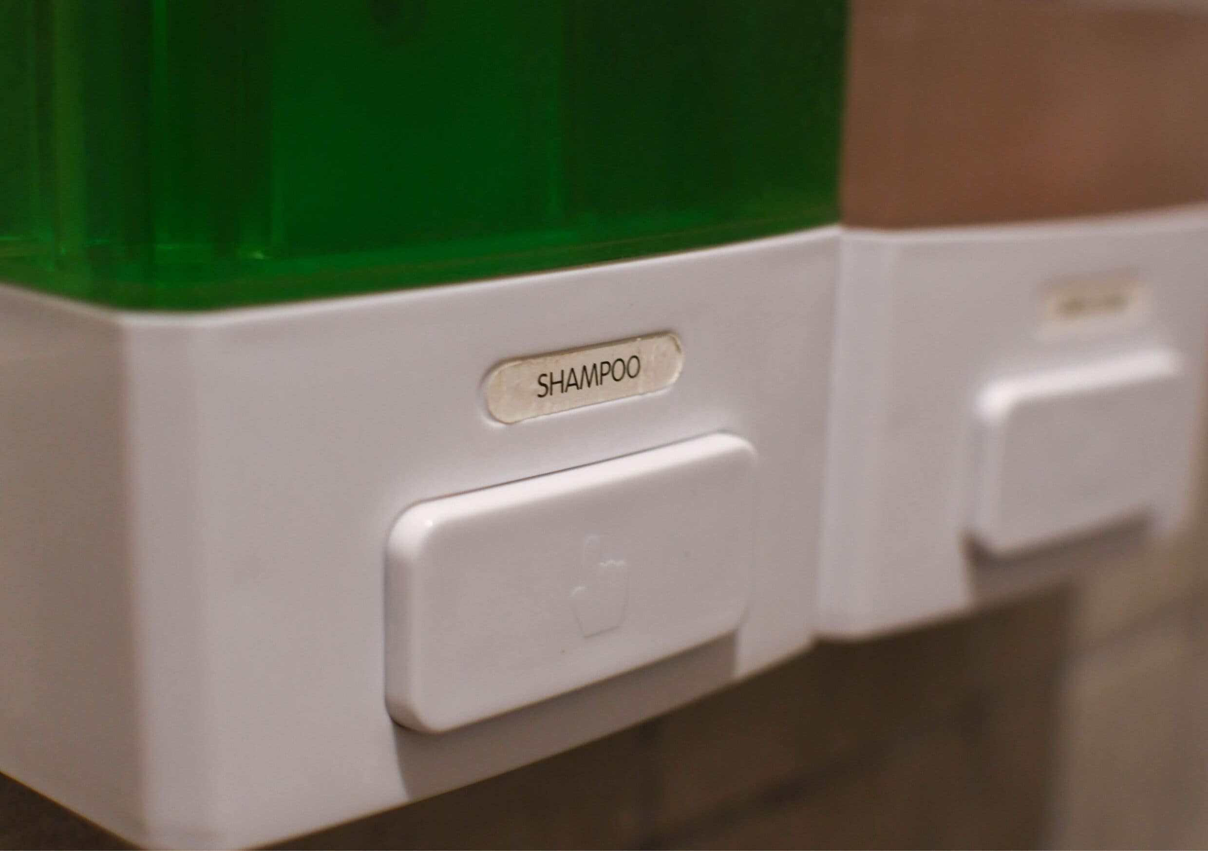 Dispensador de baño con la etiqueta 'SHAMPOO'.