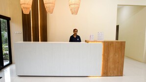Una recepción con detalles de madera, dos lámparas colgantes y un cartel con indicaciones.