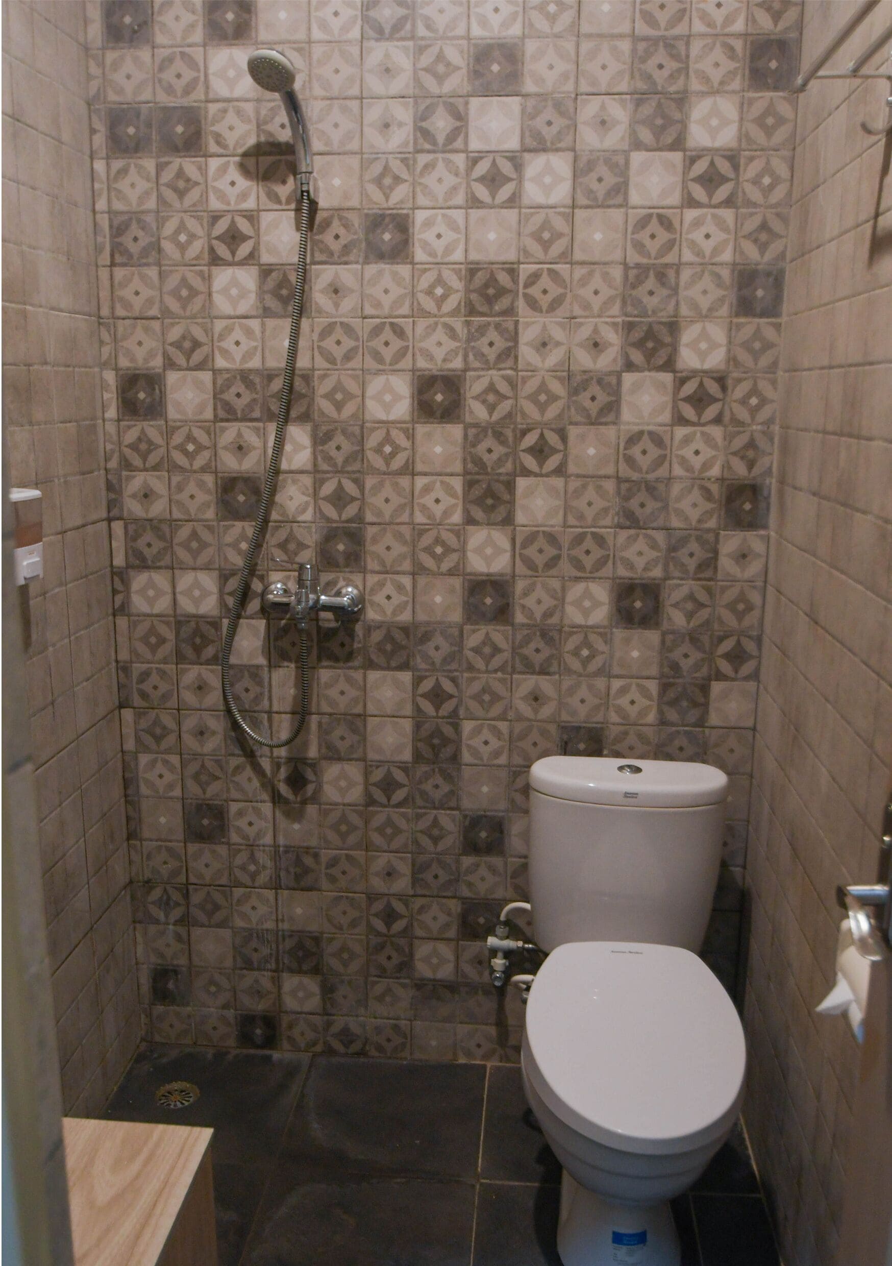 A bathroom with a toilet, shower, and tiled walls.
