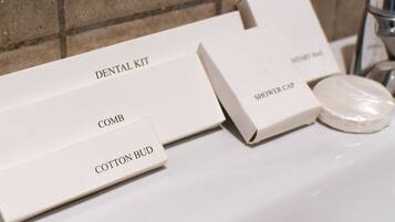 A bathroom with a white sink, a shower cap, and a dental kit.