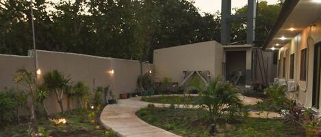 A curved concrete pathway leading to a building with a modern architectural design, surrounded by landscaped greenery and outdoor lighting.