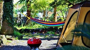 Ein Campingplatz mit Zelt, Hängematte und tragbarem Grill.