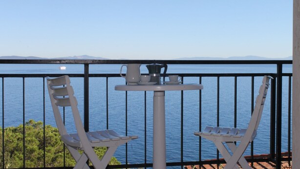 A balcony with two white chairs and a small table with a coffee pot, overlooking a calm sea with distant mountains. - Villa Porticciolo - Villa with a wonderful sea view in Rio Marina - ibookingelba (Rio Marina)