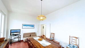 A dining area with a wooden table, chairs, and a hanging light fixture. - Villa Porticciolo - Villa with a wonderful sea view in Rio Marina - ibookingelba (Rio Marina)