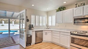 A kitchen with white cabinetry, a dishwasher, an oven, and a view of a swimming pool through a glass door. - Heated Pool, Views, & Trail Access: Phoenix Escape (Phoenix (Ahwatukee))