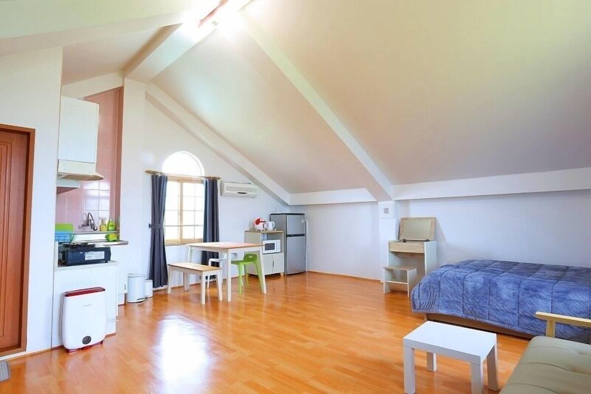 Ein geräumiges Zimmer mit einer Küchenzeile, einem Essbereich und einem Bett.