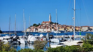 A marina with multiple sailboats docked, a prominent tower, and a densely packed town with colorful buildings in the background. - Apartments Hinterreiter (Rovinj)