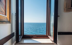 A view through a window to the sea, with a wooden floor and a framed picture on the wall. - Apartments Hinterreiter (Rovinj)