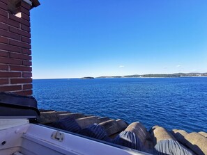 Une vue sur la mer, prise depuis une fenêtre, avec un mur de briques et des barrières en béton.