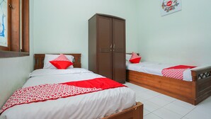 A bedroom with two beds, each with a red and white patterned bedspread, a wooden wardrobe, and a wall-mounted artwork. - OYO 1439 Gang Guest Homestay Syariah (Tuban)
