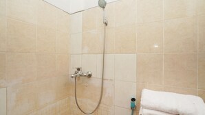 A shower with a handheld showerhead and a handheld hose, a towel rack with folded towels, and a wall-mounted faucet. - OYO 1439 Gang Guest Homestay Syariah (Tuban)