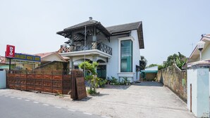 A two-story house with a balcony, a gated entrance, and a sign for a guest house and resto. - OYO 1439 Gang Guest Homestay Syariah (Tuban)