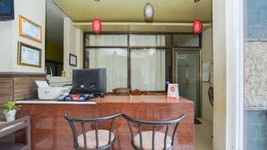 A small bar area with a wooden counter, two bar stools, a television, and a menu stand. - OYO 1439 Gang Guest Homestay Syariah (Tuban)