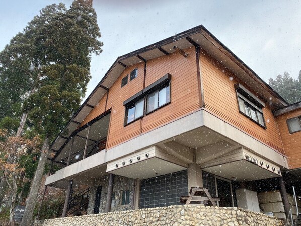 A modern two-story building with a stone foundation, large windows, and a covered outdoor area. - Guest House Nishiborakan - Hostel (Gujo)
