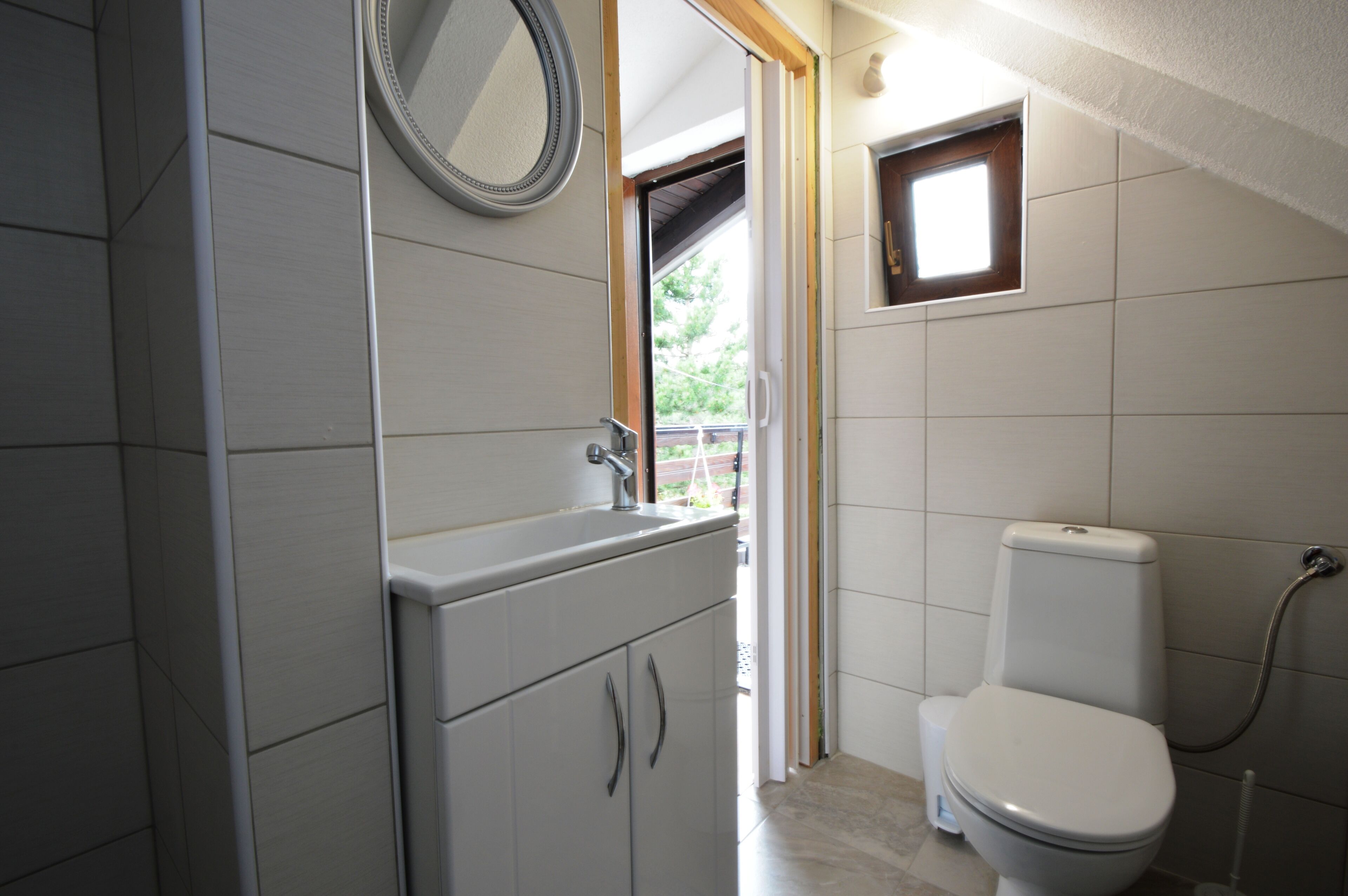 A bathroom with a toilet, sink, and mirror.