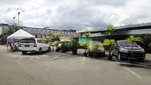 A parking lot with several cars and potted plants. - Hotel O Os Residence (Medan)