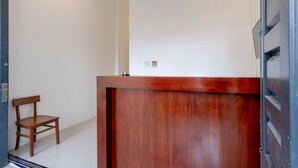 A wooden reception desk with a chair to the left. - Hotel O Os Residence (Medan)