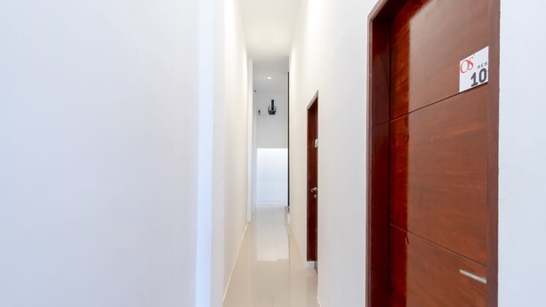 A hallway with a wooden door marked "10" and a sign indicating "OS RESERV". - Hotel O Os Residence (Medan)