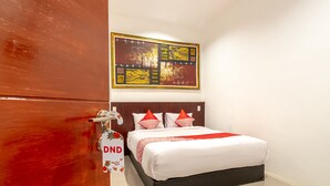 A hotel room with a bed, a painting on the wall, and a door with a DND sign. - Hotel O Os Residence (Medan)