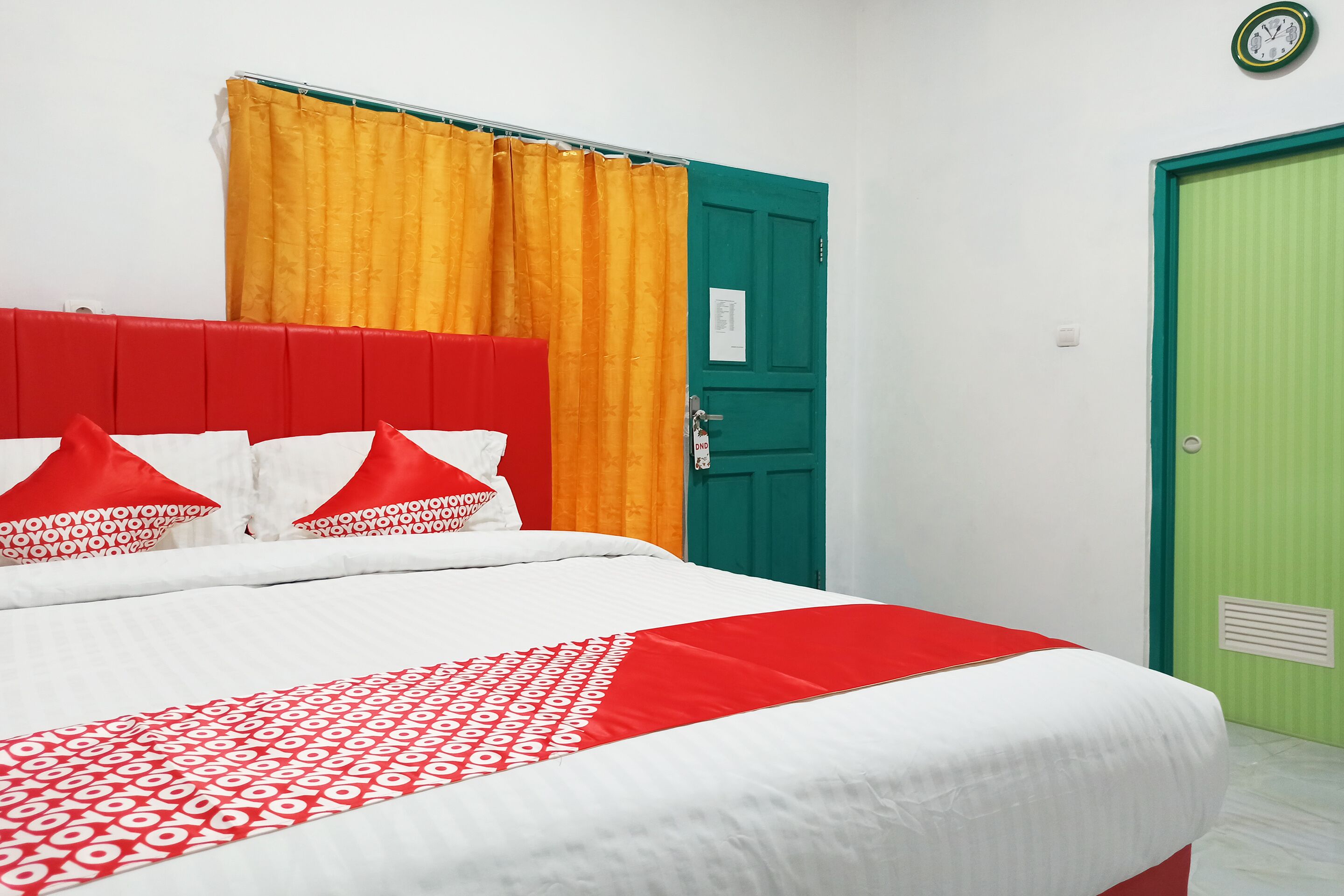 A bed with a red headboard, white bedding, and red and white pillows.