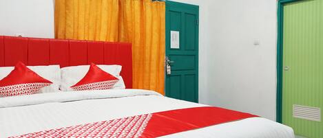 A bed with a red headboard, white bedding, and red and white pillows.