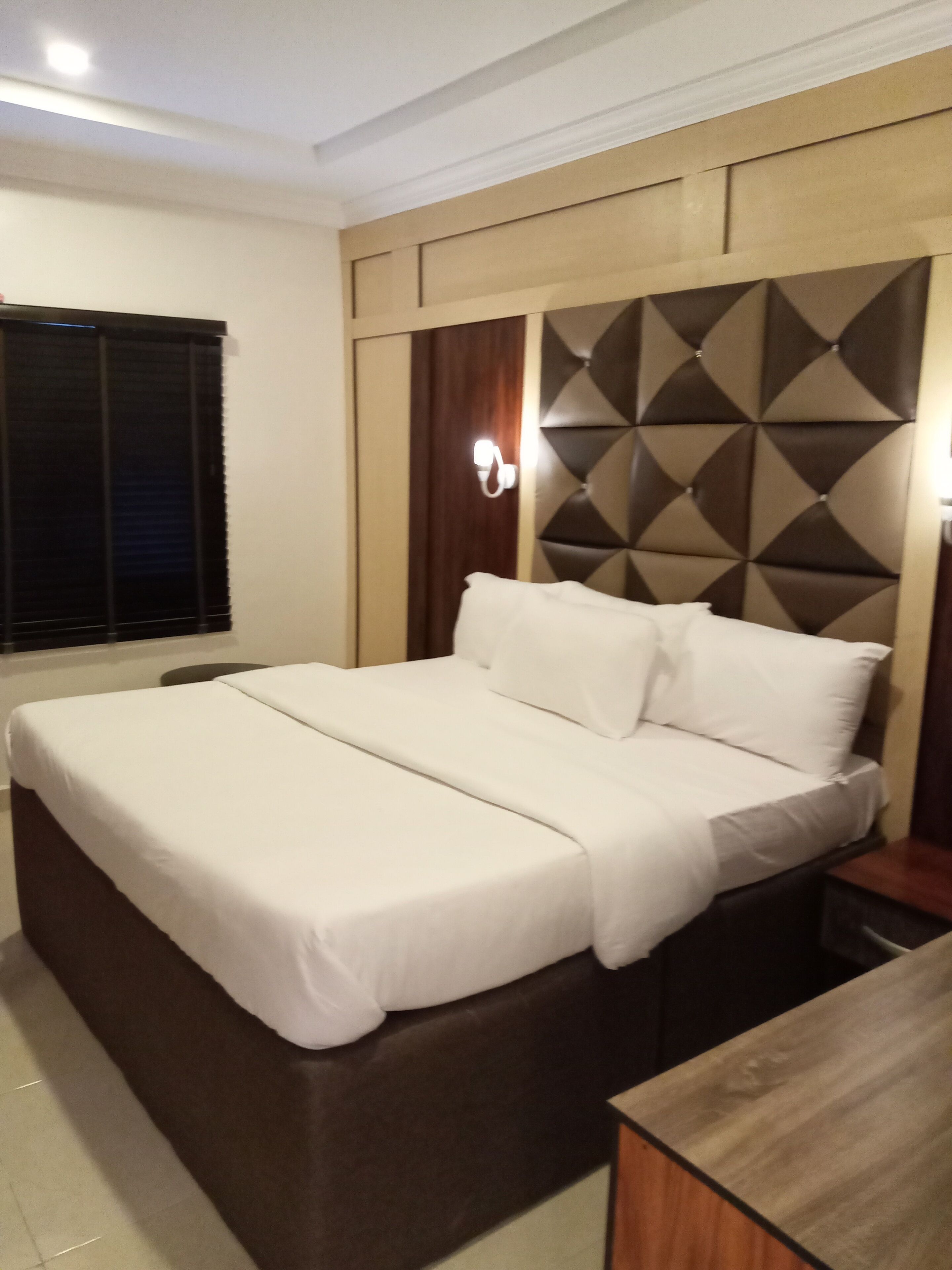 Une chambre d’hôtel moderne avec un grand lit, une tête de lit en bois et une table de chevet.