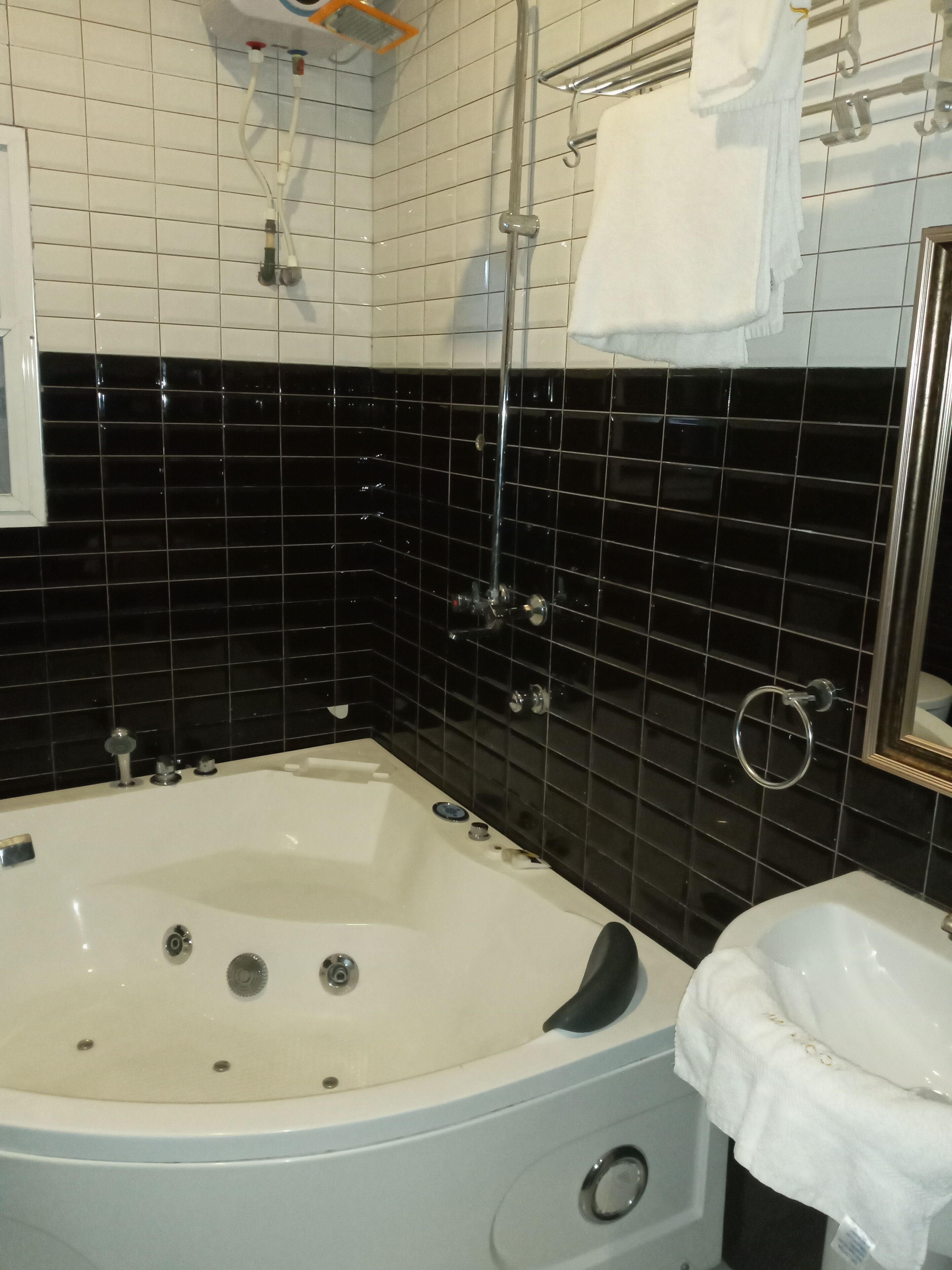 Une salle de bain avec une baignoire blanche, des murs recouverts de carreaux noirs et un lavabo blanc.