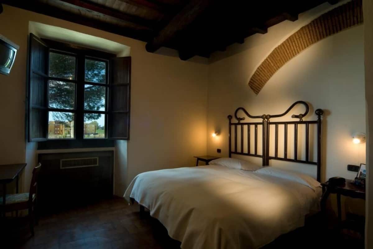 A bedroom with a bed, a window, a fireplace, and a curved ceiling.