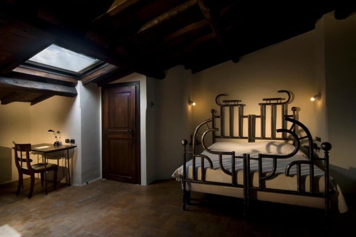 Un dormitorio con tragaluz, cama, escritorio y silla.