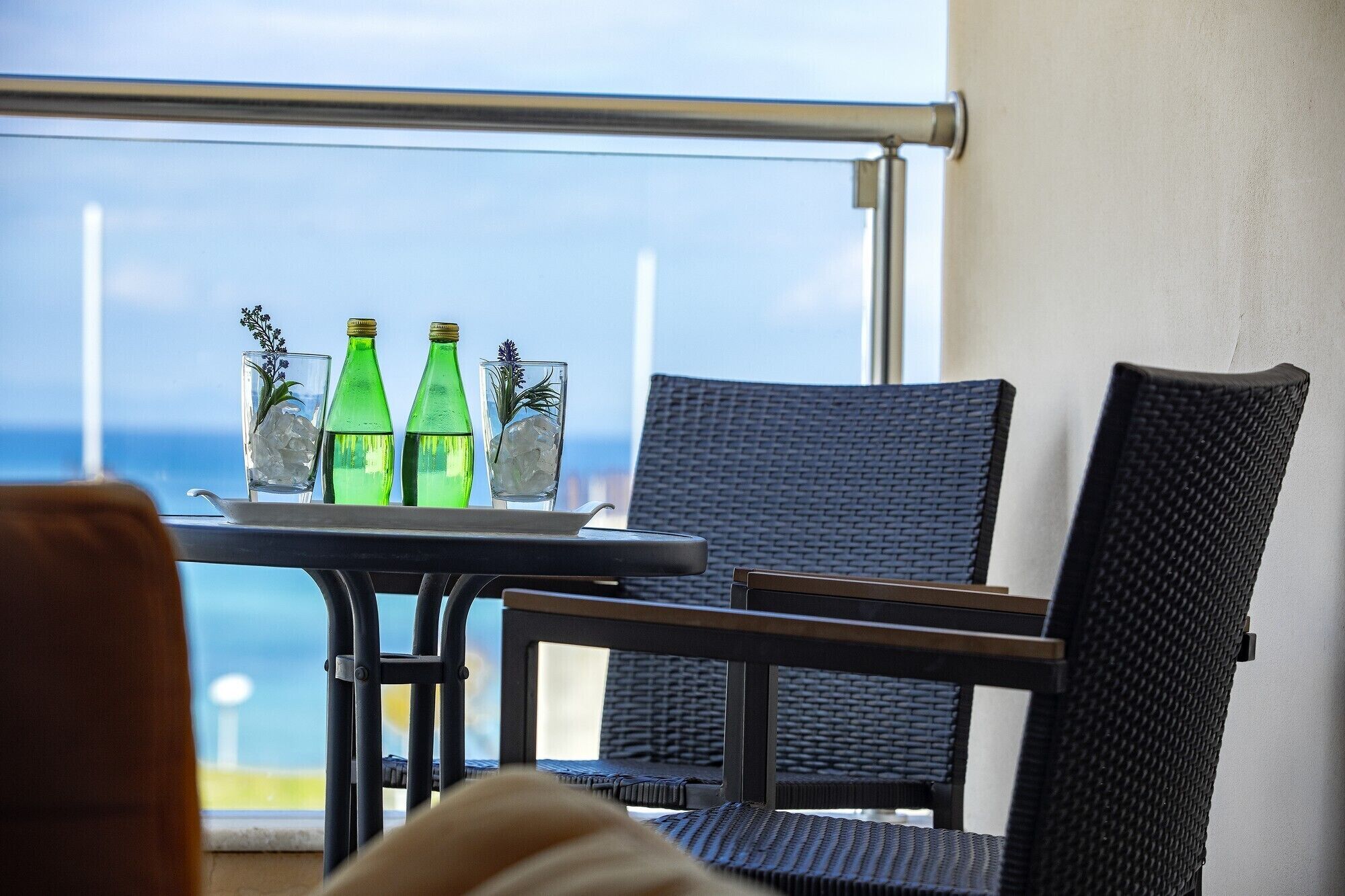 Un balcón con mesa y sillas, con vista al mar.